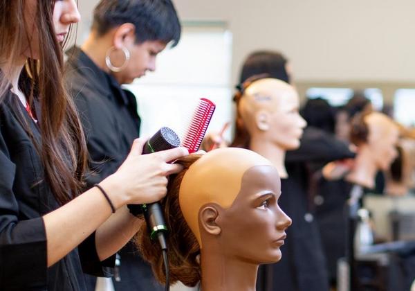 Women practicing their hairdressing skills on dummies