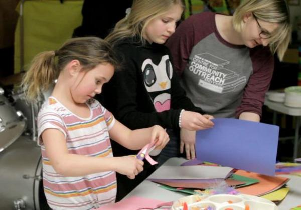 Young woman with glasses and two girls doing crafts together