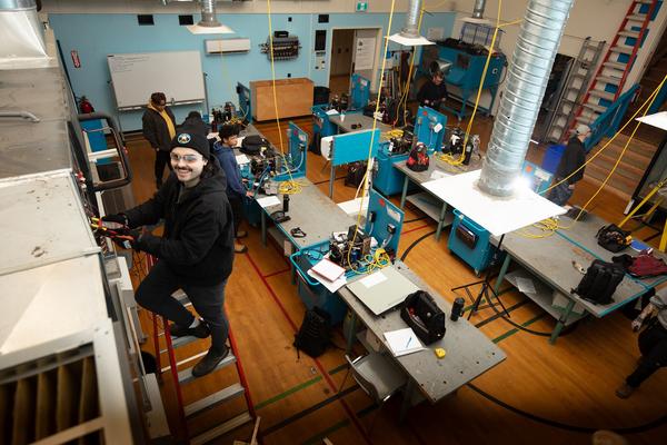 Young man on a step ladder working on an HVAC unit