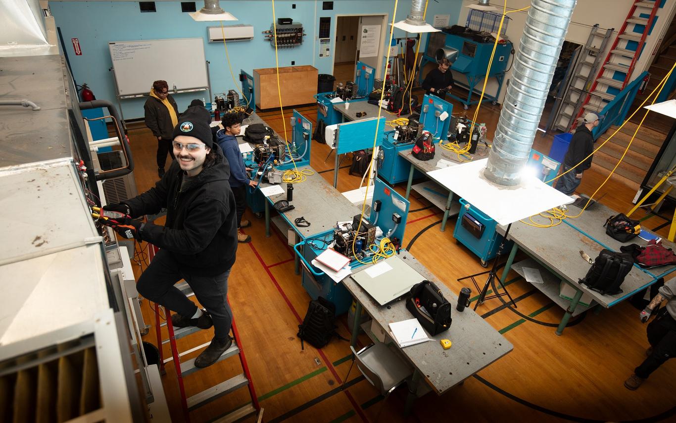 Young man on a step ladder working on an HVAC unit