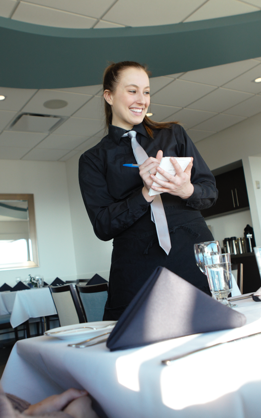 Smiling Hospitality student serving two dining customers